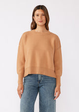 [Color: Camel] A brunette model wearing a solid brown, tan sweater crafted in a comfy knit with a relaxed, boxy silhouette. Featuring long sleeves with dropped shoulders, a crew neckline, and ribbed trims. Perfectly cozy and casual for everyday styling. 