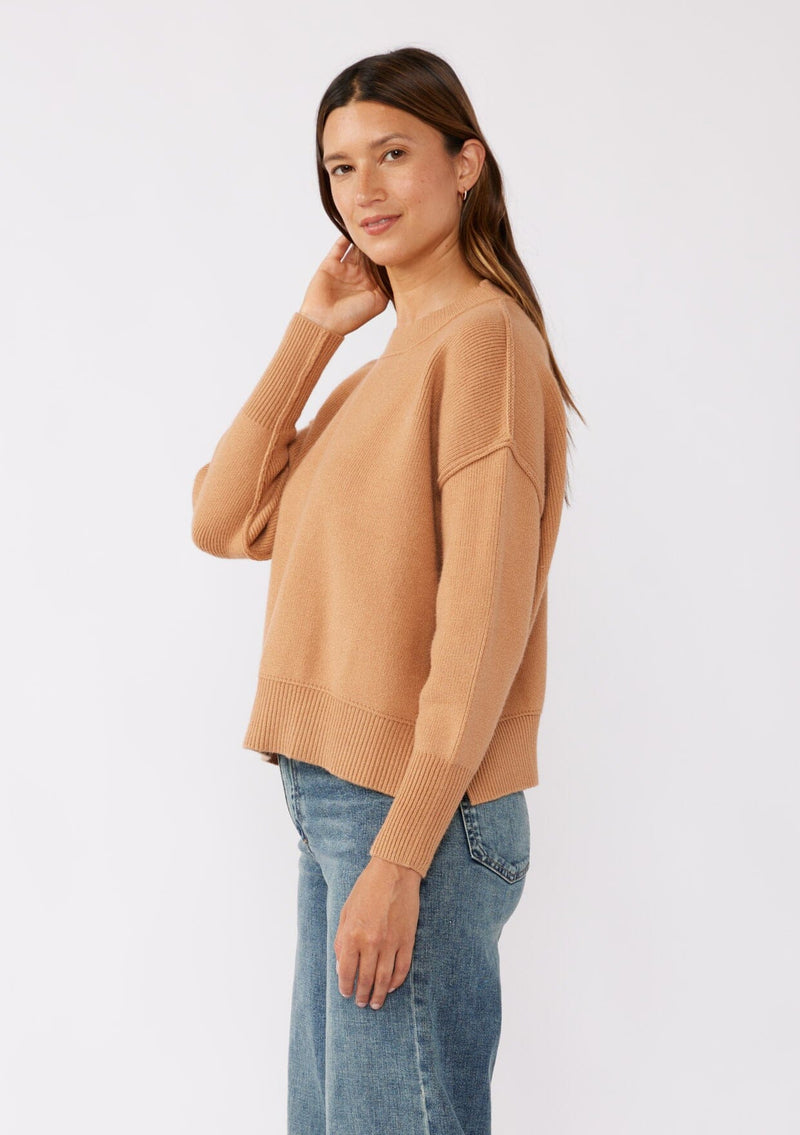 [Color: Camel] A brunette model wearing a solid brown, tan sweater crafted in a comfy knit with a relaxed, boxy silhouette. Featuring long sleeves with dropped shoulders, a crew neckline, and ribbed trims. Perfectly cozy and casual for everyday styling. 