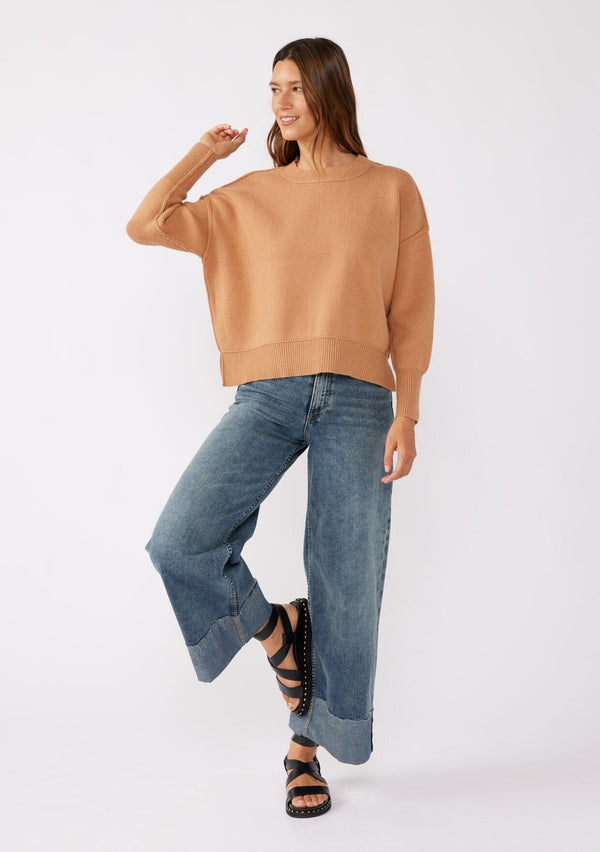 [Color: Camel] A brunette model wearing a solid brown, tan sweater crafted in a comfy knit with a relaxed, boxy silhouette. Featuring long sleeves with dropped shoulders, a crew neckline, and ribbed trims. Perfectly cozy and casual for everyday styling. 