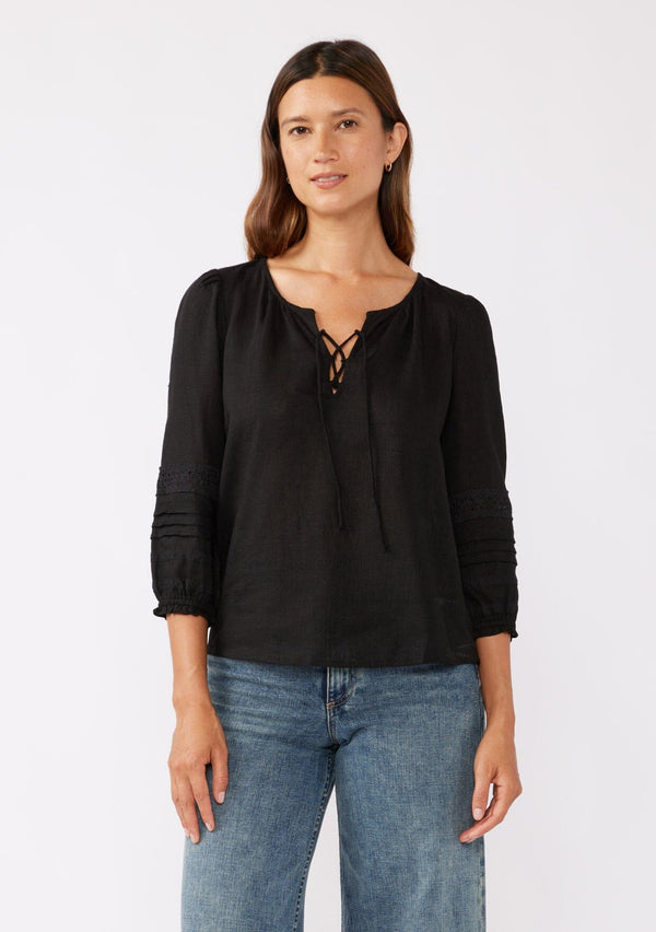 [Color: Black] A brunette model wearing a bohemian black blouse with embroidered lace details. Crafted from a rayon and linen blend, this top feature long sleeves, a lace up front, and elastic cuffs. Perfect addition to any fall bohemian wardrobe.  