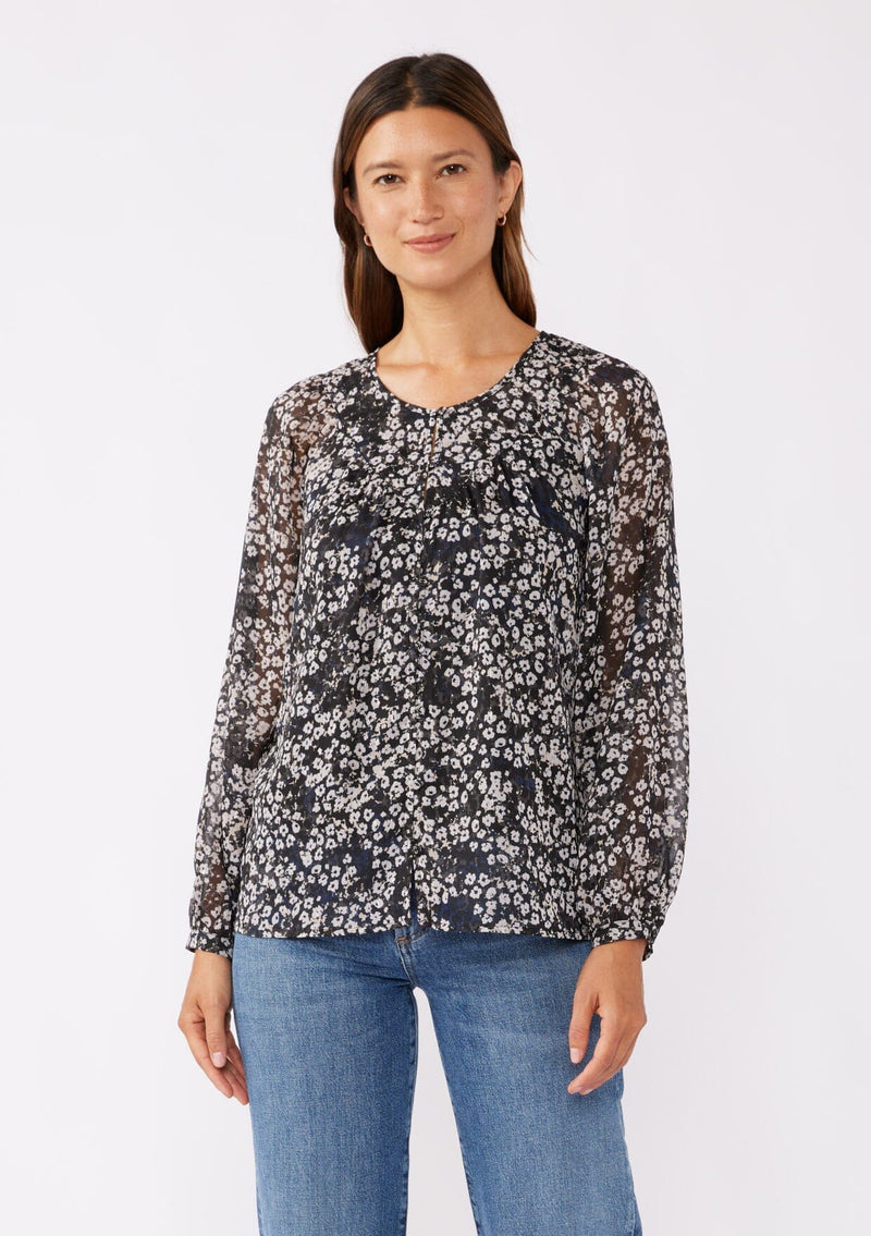 [Color: Black/Grey] A brunette model wearing a relaxed fit blouse in black and ivory floral print with shimmering metallic clip dot details. A classic, timeless blouse in a flowy chiffon with long sleeves and a button front. Perfect for the office or late night dinners.  