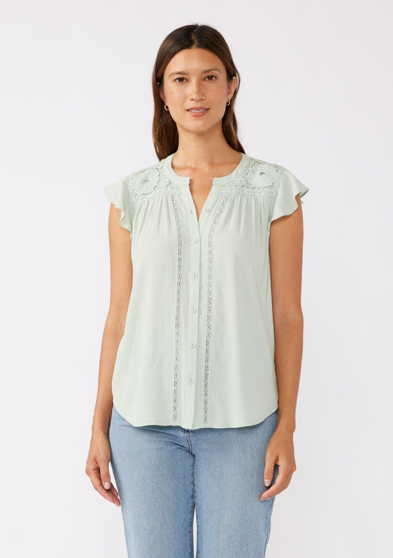 [Color: Mint] A brunette model wearing a classic Lovestitch button up top in green mint. With short flutter sleeves, split v neckline, and a floral lace trim at the yoke. Perfect for the summer and beyond. 