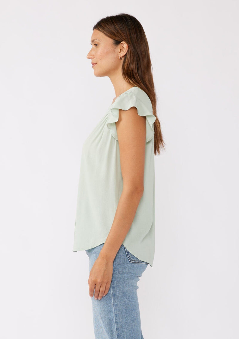 [Color: Mint] A brunette model wearing a classic Lovestitch button up top in green mint. With short flutter sleeves, split v neckline, and a floral lace trim at the yoke. Perfect for the summer and beyond.