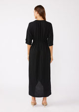 [Color: Black/Natural] A brunette model wearing a black front knot maxi dress with a contrast embroidery, Featuring a deep v neckline, kimono sleeves, front slit, and an asymmetrical hem. A bohemian style maxi dress with a relaxed fit.