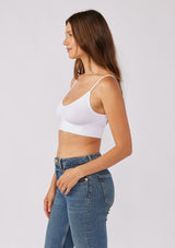 [Color: White] A brunette model wearing a fitted crop lingerie top in white. A casual yet stylish undergarment perfect for styling under dresses or wearing on it's own as a sports bra. A comfortable stretchy ribbed knit top with a low back and spaghetti straps.