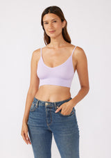 [Color: Lilac] A brunette model wearing a fitted crop lingerie top in purple. A casual yet stylish undergarment perfect for styling under dresses or wearing on it's own as a sports bra. A comfortable stretchy ribbed knit top with a low back and spaghetti straps.