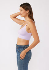 [Color: Lilac] A brunette model wearing a fitted crop lingerie top in purple. A casual yet stylish undergarment perfect for styling under dresses or wearing on it's own as a sports bra. A comfortable stretchy ribbed knit top with a low back and spaghetti straps.