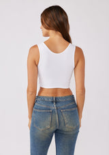 [Color: White] A brunette model wearing a reversible crop top bandeau in white from By Together. With a stretchy fit, soft knit fabric, and chic twist front.