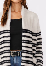 [Color: Grey/Black] A brunette model wearing a fuzzy mid length cardigan with mirrored black stripes. A soft long sleeve cardigan with an open front, shawl collar, and patch pockets. An everyday sweater for the fall season. 