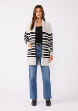 [Color: Grey/Black] A brunette model wearing a fuzzy mid length cardigan with mirrored black stripes. A soft long sleeve cardigan with an open front, shawl collar, and patch pockets. An everyday sweater for the fall season. 