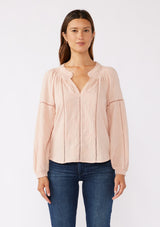 [Color: Dusty Rose] A front facing image of a brunette model wearing a pretty boho blouse in a dusty pink. With floral tonal embroidery, lace trim inserts, long sleeves with smocked wrist cuffs, and a split v neckline. An airy and relaxed fit blouse crafted in a cotton blend fabric. 