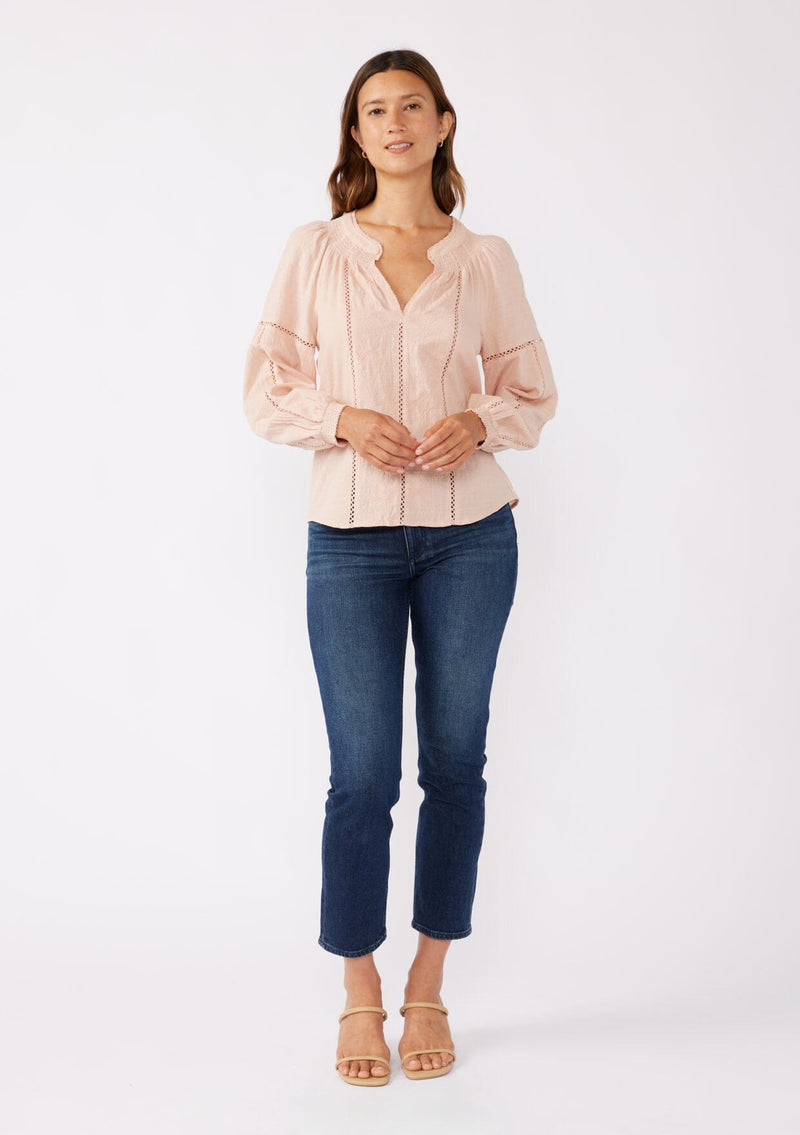 [Color: Dusty Rose] A front facing image of a brunette model wearing a pretty boho blouse in a dusty pink. With floral tonal embroidery, lace trim inserts, long sleeves with smocked wrist cuffs, and a split v neckline. An airy and relaxed fit blouse crafted in a cotton blend fabric. 