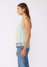 [Color: Mint] A side facing image of a brunette model wearing a green mint bohemian top with floral lace details. This sleeveless design features adjustable spaghetti straps, delicate lace trims, and a smocked back. Perfect for everyday styling.     