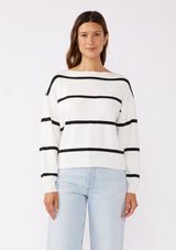 [Color: White/Black] A brunette model wearing a classic black and white striped knit pullover sweater. With long sleeves, a boat neckline, and ribbed trims. Perfectly relaxed and boxy for everyday styling. 