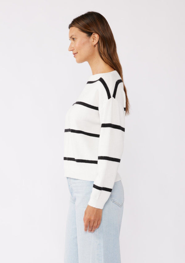 [Color: White/Black] A brunette model wearing a classic black and white striped knit pullover sweater. With long sleeves, a boat neckline, and ribbed trims. Perfectly relaxed and boxy for everyday styling. 