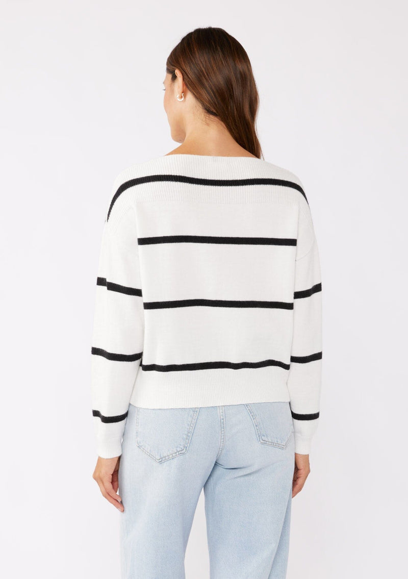 [Color: White/Black] A brunette model wearing a classic black and white striped knit pullover sweater. With long sleeves, a boat neckline, and ribbed trims. Perfectly relaxed and boxy for everyday styling. 