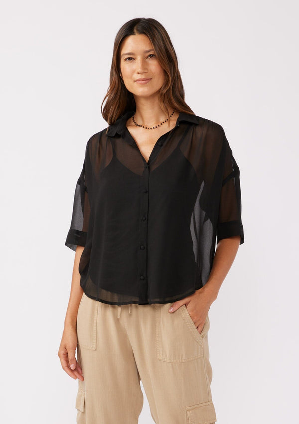 [Color: Black] A front facing image of a brunette model wearing a black sheer chiffon short sleeve button front blouse. With a self covered button front and a collared neckline.