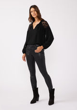 [Color: Black] A front facing image of a brunette model wearing a black bohemian fall blouse with long sleeves, a split v neckline with ties, and sheer embroidered mesh detail along the shoulders.