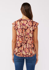 [Color: Wine/Dusty Rose] A back facing image of a brunette model wearing a red and orange bohemian floral print blouse. This autumn-inspired blouse features a double tassel tie front, short flutter sleeves, and a relaxed fit. 