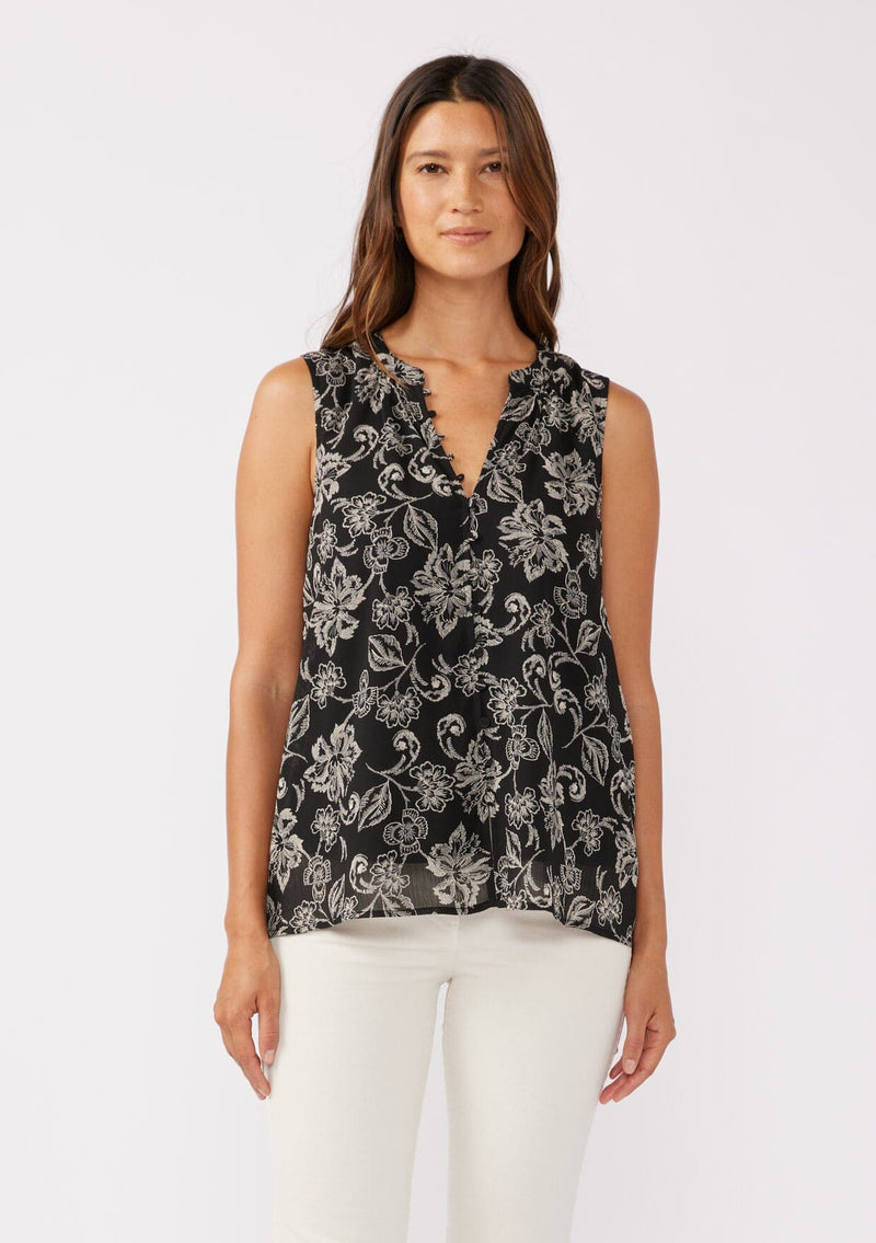 [Color: Black/Natural] A front facing image of a brunette model wearing a classic sleeveless bohemian tank top in a black and natural, off white floral print. A flowy chiffon top with a button front and loop button trimmed v neckline.