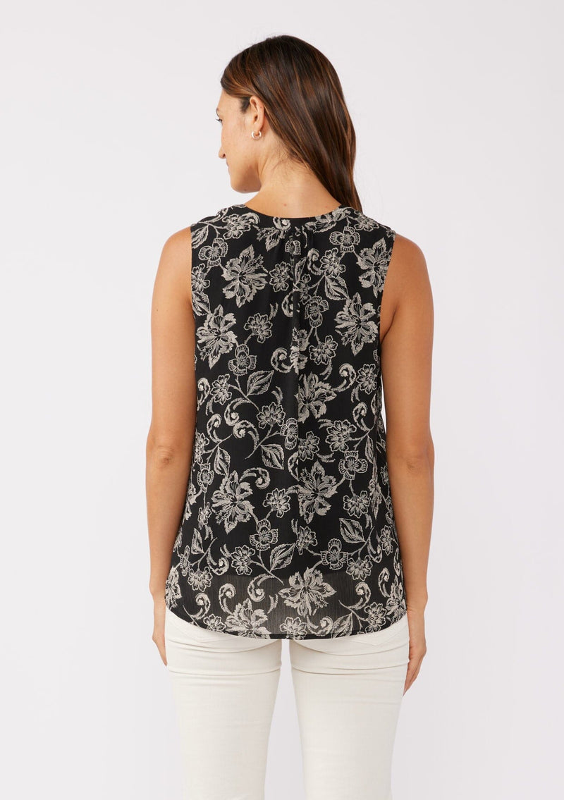 [Color: Black/Natural] A back facing image of a brunette model wearing a classic sleeveless bohemian tank top in a black and natural, off white floral print. A flowy chiffon top with a button front and loop button trimmed v neckline.