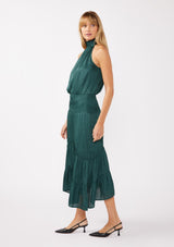 [Color: Teal] A full body side facing image of a blonde model wearing a green holiday halter maxi dress with a sleeveless design, smocked drop waist, and a tiered skirt. This flowy satin dress is perfect for any special occasion and holiday events. 