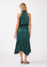 [Color: Teal] A full body back facing image of a blonde model wearing a green holiday halter maxi dress with a sleeveless design, smocked drop waist, and a tiered skirt. This flowy satin dress is perfect for any special occasion and holiday events. 