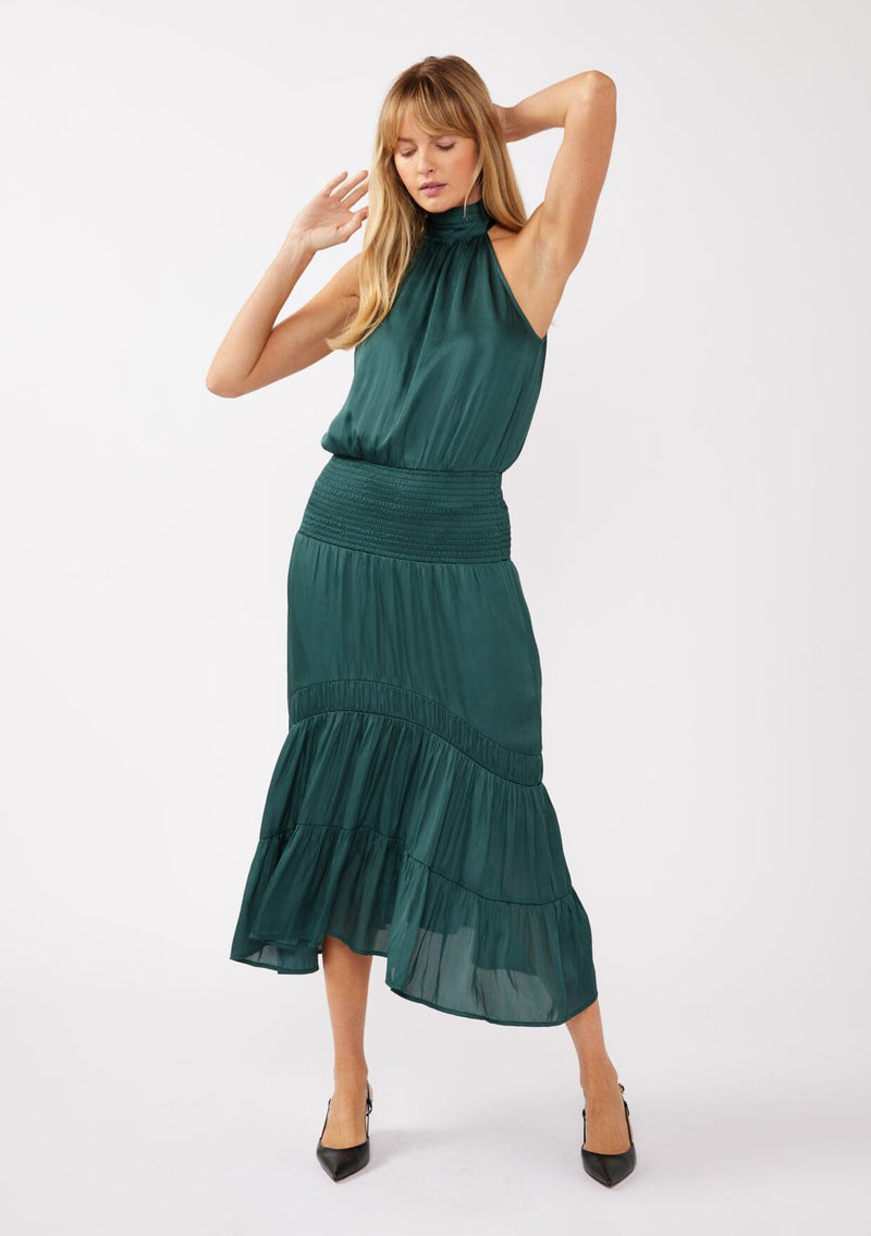 [Color: Teal] A full body front facing image of a blonde model wearing a green holiday halter maxi dress with a sleeveless design, smocked drop waist, and tiered skirt. This flowy satin dress is perfect for any special occasion and holiday events. 