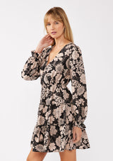 [Color: Black/Taupe] A side-facing image of a blonde model wearing a black and taupe floral print mini dress. This casual boho style features a surplice v-neckline, long sleeves with ruffled cuffs, and a flowy tiered skirt. Ideal for casual brunch outings, vacations, and special occasions.