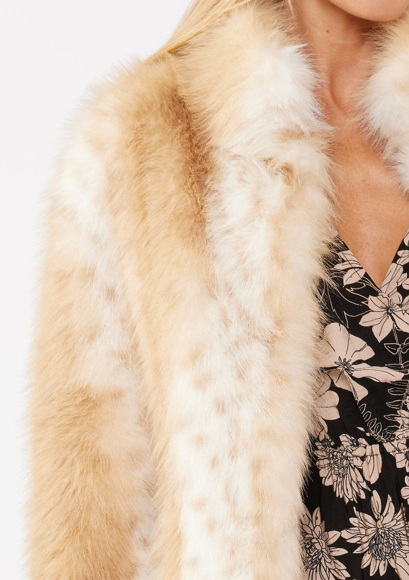 [Color: Natural] A detail image of a blonde model wearing a tan brown stripe, dotted fur faux coat over a floral dress. Featuring a high collar, open front, and long sleeves. A cold weather style, perfect for any special occasion. 