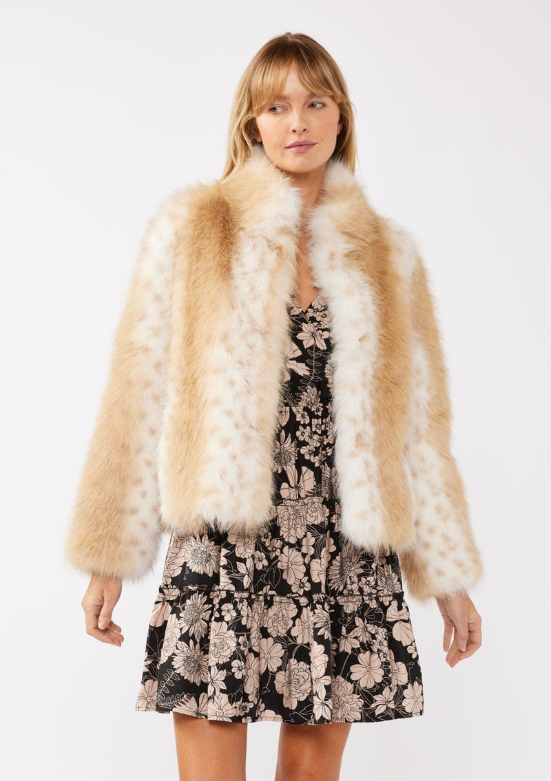 [Color: Natural] A front facing image of a blonde model wearing a tan brown stripe, dotted fur faux coat over a floral dress. Featuring a high collar, open front, and long sleeves. A cold weather style, perfect for any special occasion. 