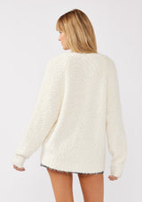 [Color: Antique White] A back-facing image of a blonde model wearing a green cozy, fuzzy popcorn-textured pullover sweater with long sleeves, a classic V-neckline, and a high-low hemline. Ideal for lounging or casual fall outings.