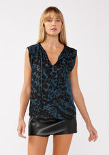 [Color: Midnight/Black] A front facing image of a blonde model wearing a blue and black leopard print top. The top features a split V-neckline with tie detail, cap sleeves, and a relaxed silhouette. A versatile holiday top, ideal for both work and special occasions.