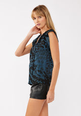 [Color: Midnight/Black] A side facing image of a blonde model wearing a blue and black leopard print top. The top features a split V-neckline with tie detail, cap sleeves, and a relaxed silhouette. A versatile holiday top, ideal for both work and special occasions.