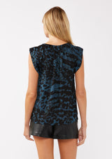 [Color: Midnight/Black] A back facing image of a blonde model wearing a blue and black leopard print top. The top features a split V-neckline with tie detail, cap sleeves, and a relaxed silhouette. A versatile holiday top, ideal for both work and special occasions.