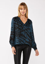 [Color: Midnight/Black] A front facing image of a blonde model wearing a leopard print blouse in black and blue. With a split v-neckline, smocked cuffs, and a smocked back detail. Ultra relaxed and flowy, perfect work and special occasions. 