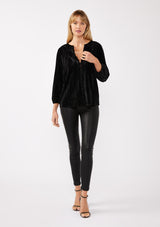 [Color: Black ] A front facing full body image of a blonde model wearing a black velvet blouse with a loop button front, long sleeves, and elastic cuffs. The boho-inspired holiday blouse is paired with black faux leather bottoms for a chic nighttime look.