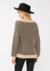 [Color: Natural/Black] A back image of a blonde model wearing a striped knit pullover with a bold contrast. Featuring a collared v-neckline, long sleeves, dropped shoulders, and a ribbed cuffs and hem. A relaxed knit sweater styled with black bottoms for the fall season. 