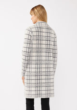 [Color: Cream/Black] A back facing image of a blonde model wearing a fuzzy statement sweater coat in a cream and black plaid print. With long sleeves, a notched collar, a snap button front, and side patch pockets. 