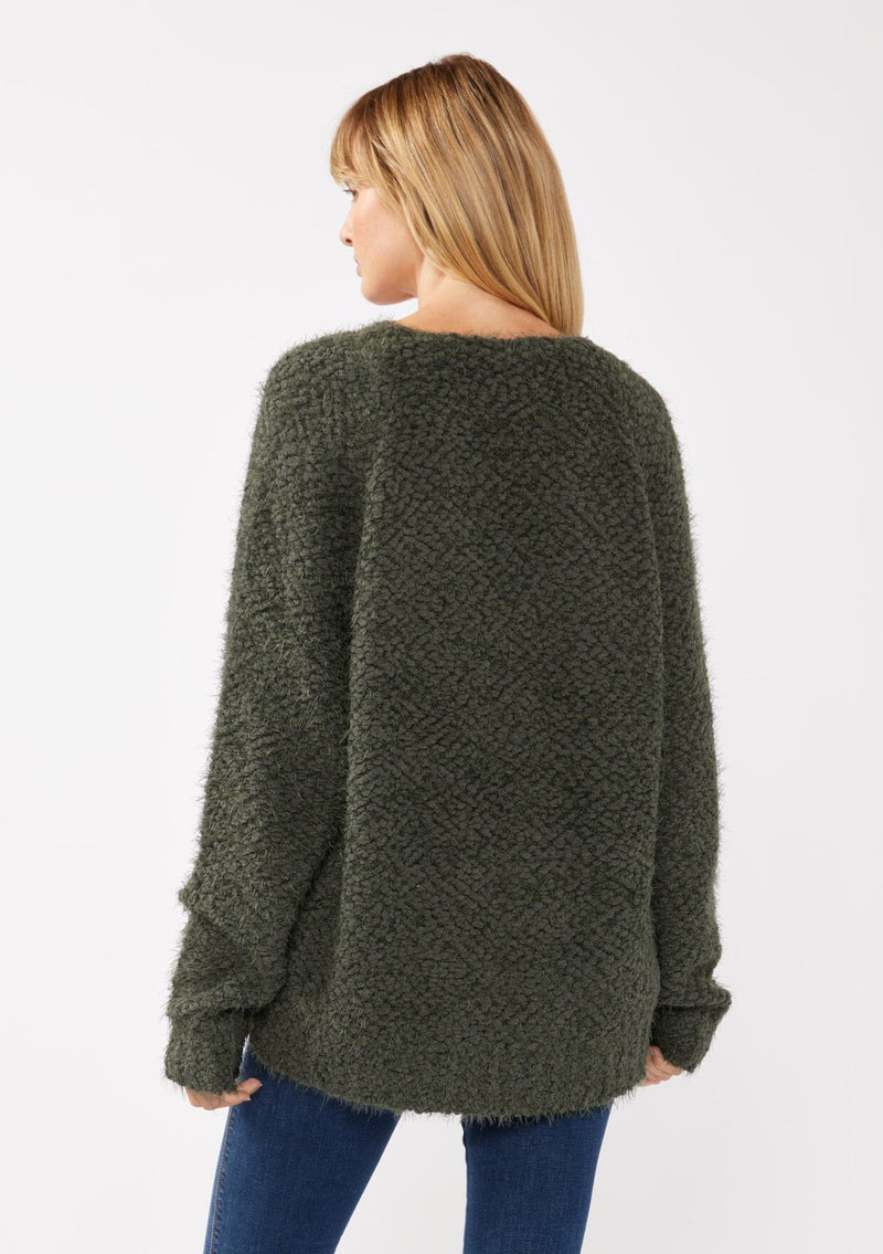 [Color: Olive] A back-facing image of a blonde model wearing a green cozy, fuzzy popcorn-textured pullover sweater with long sleeves, a classic V-neckline, and a high-low hemline. Ideal for lounging or casual fall outings.