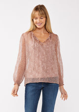 [Color: Mauve] A front facing image of a blonde model wearing a crinkled sheer chiffon blouse with a floral pattern. This relaxed fit blouse features a double tie neck detail, long sleeves with ruffled elastic cuffs, and a detachable cami. 