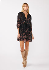 [Color: Black/Dusty Rose] A full body image of a blonde model wearing a black chiffon mini dress with a pink floral print. The boho-inspired design features a split V-neckline, button front, 3/4 sleeves, and an adjustable drawstring waist. Paired with long suede boots for a casual yet polished fall look.