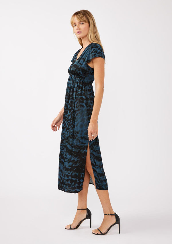 [Color: Midnight/Black] A full body side facing image of a blonde model wearing a black and blue leopard print maxi dress. With a deep v neckline, short sleeves, elastic waistline, and side slits. A versatile holiday dress, perfect for casual outings and special occasions. 