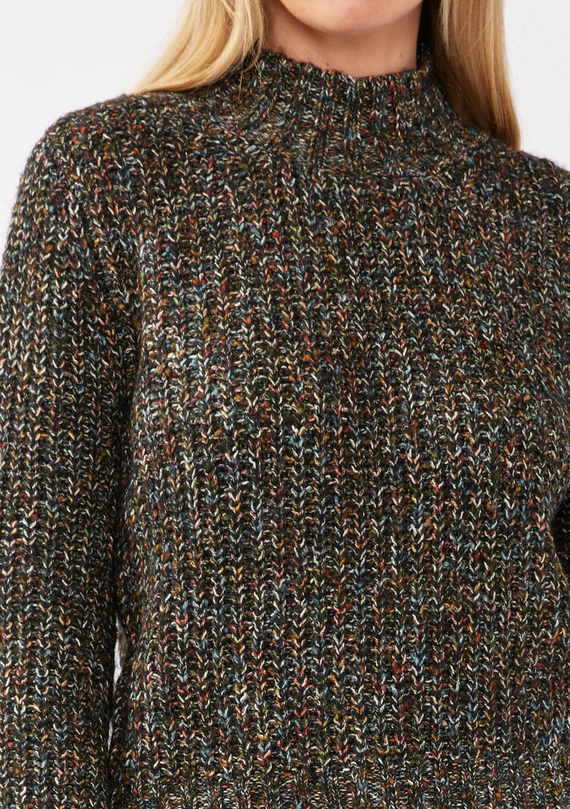 [Color: Black Multi] A detail image of a blonde model wearing a chunky multi color knit sweater with a mock neckline and long voluminous sleeves. 