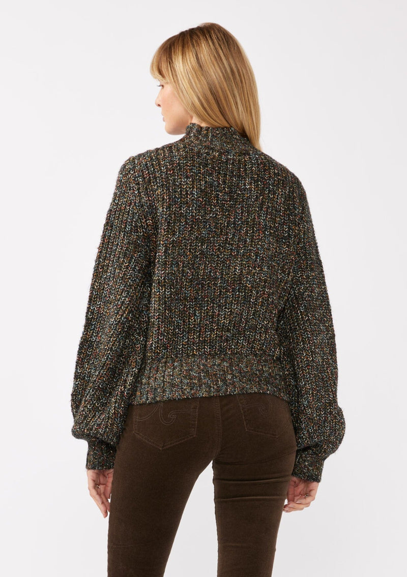 [Color: Black Multi] A back facing image of a blonde model wearing a chunky multi color knit sweater with a mock neckline and long voluminous sleeves. 