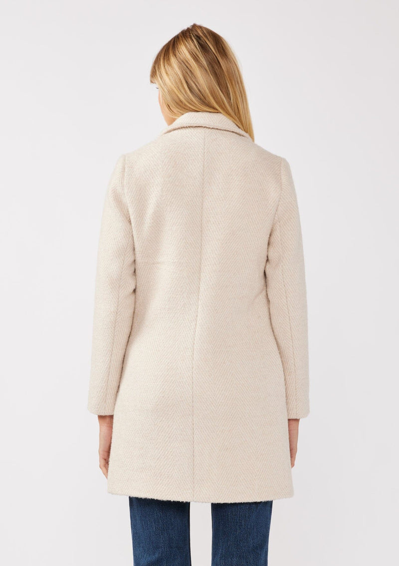 [Color: Natural/Sand] A back facing image of a blonde model wearing classic mid length coat in off white. This chevron textured coat features a classic notched lapel, a button front, and side pockets. A closet staple for the fall and winter season. 