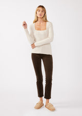 [Color: Heather Stone] A front facing full body image of a blonde model wearing a classic body hugging pullover sweater in off white. With a classic square neckline, long sleeves, and a straight hem. Styled with corduroy bottoms for a laid-back cool girl fall ensemble.   