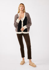 [Color: Vanilla Black] A full body front facing image of a blonde model wearing an ultra warm color block cardigan in a soft fuzzy popcorn texture. Featuring a classic tortoiseshell button up front, a flattering v neckline, and a contrast trim. This fuzzy cardigan is perfect for layering during the fall season. 