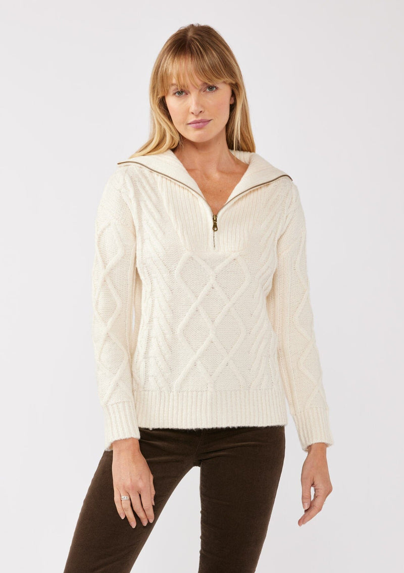 [Color: Natural] A front facing image of a blonde model wearing a cozy cable knit pullover sweater in off white. This casual fall knit features a front half zipper front, long sleeves, and a rib trim hem and cuffs. 