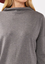 [Color: Heather Charcoal] A detail image of a blonde model wearing a grey cozy lightweight pullover with a mock neckline. Complete with long sleeves, dropped shoulders, and a snugged ribbed trim. Perfect for layering or styling on its own for a relaxed, laid-back fall look. 